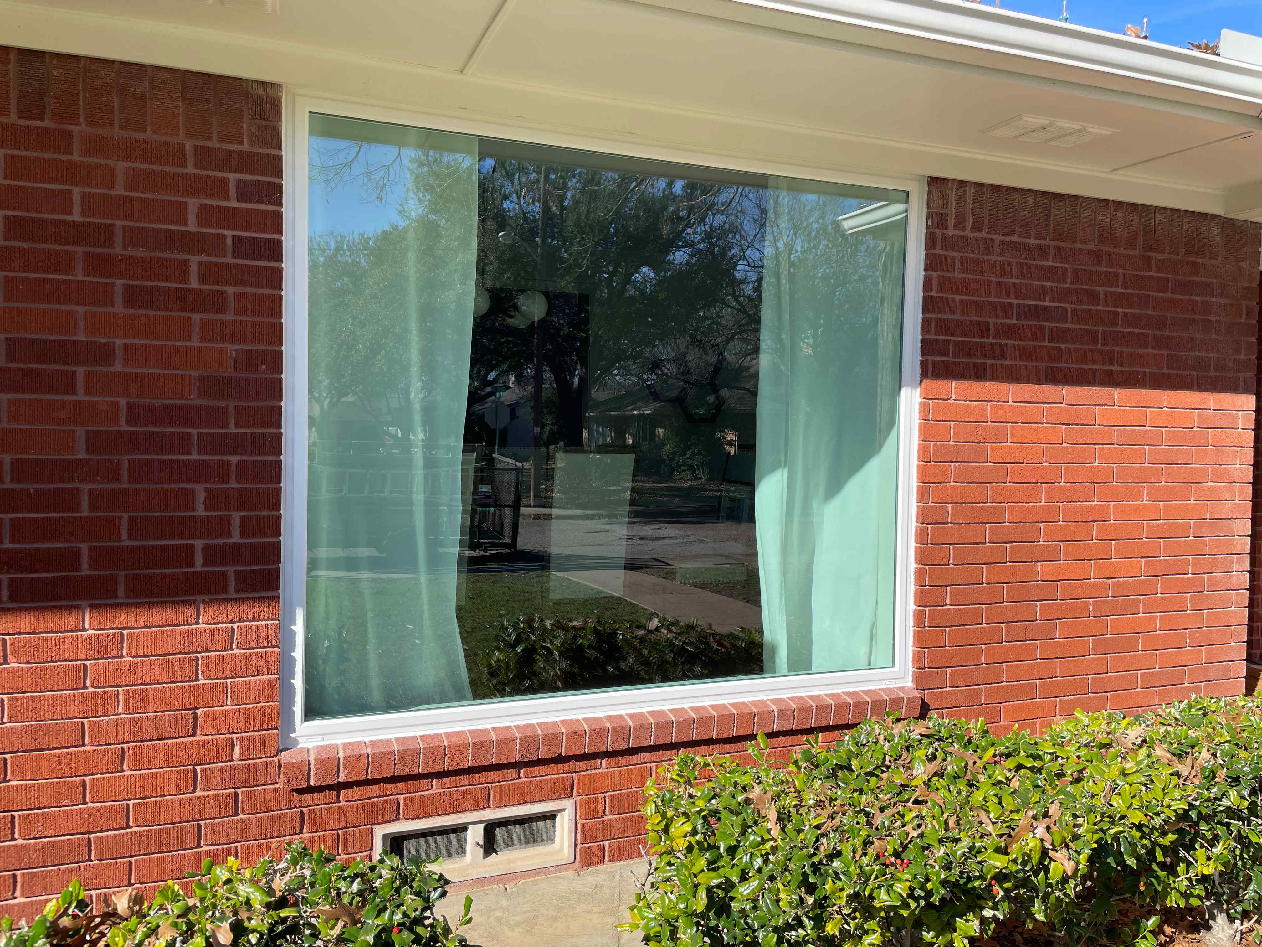 Large white-framed picture window with grid pattern on red brick exterior