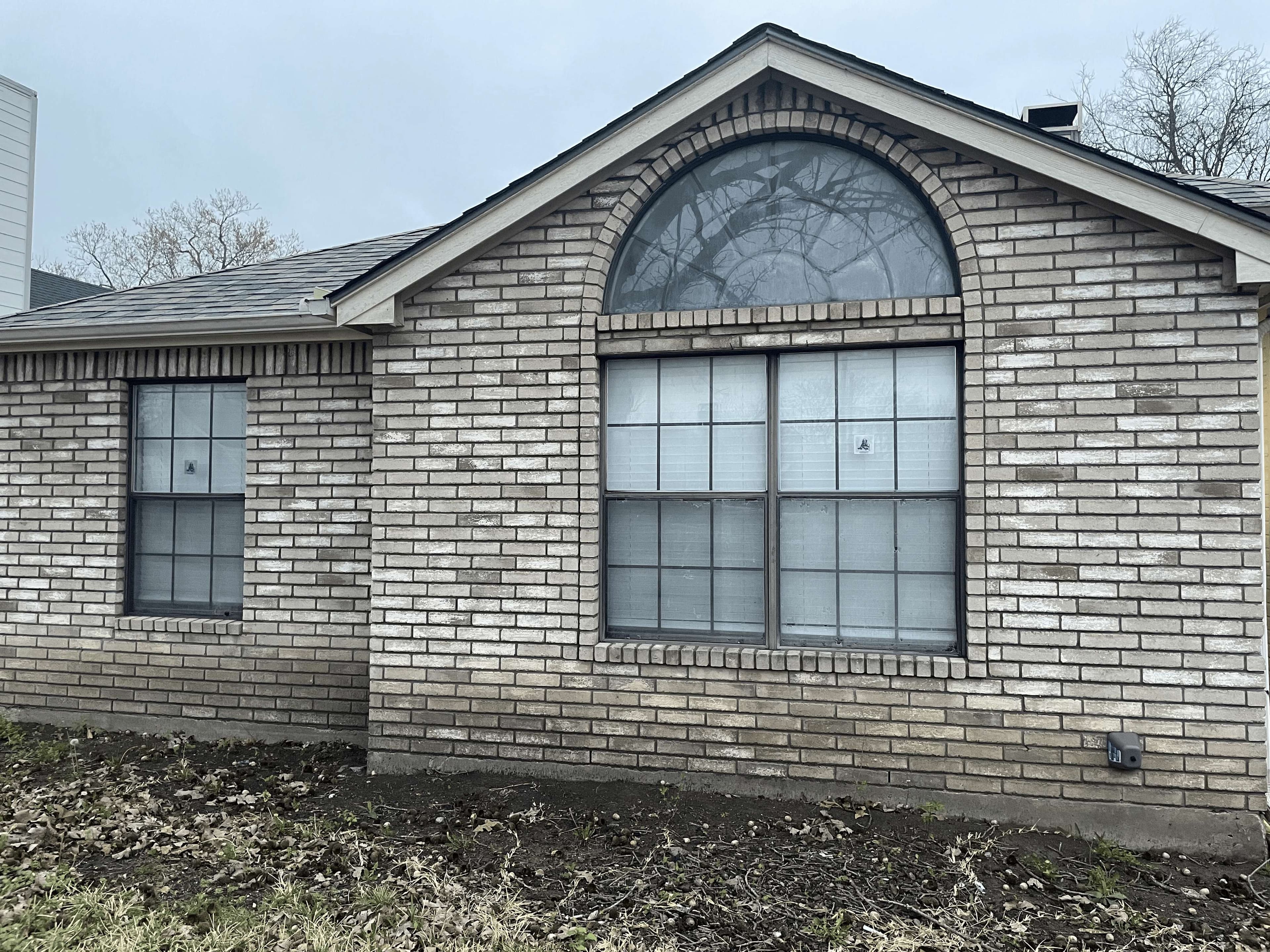 Before: Before and after: brick home with arched window - old dark frames replaced with new white frames