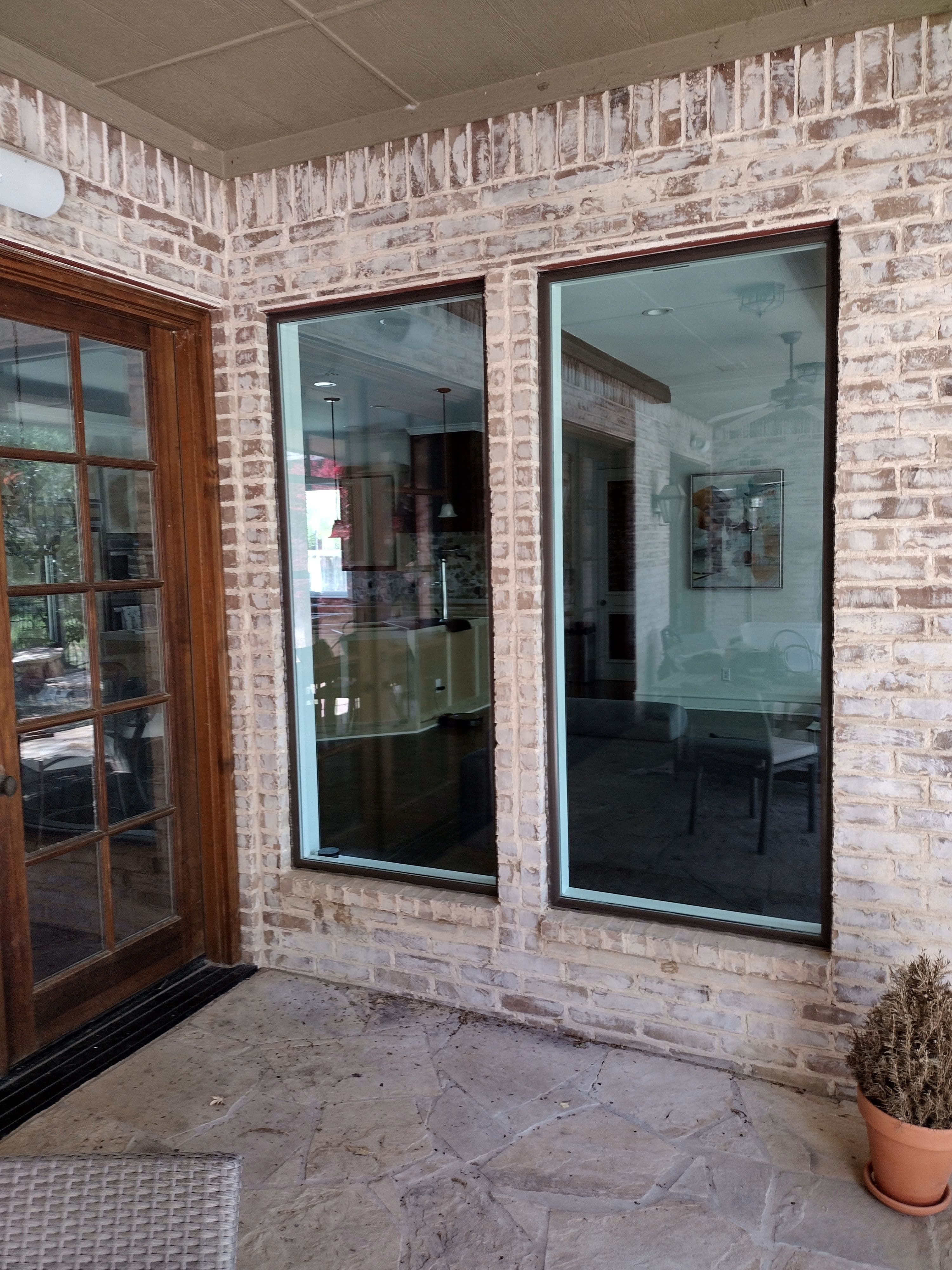 Modern black-framed picture windows installed on white brick patio area