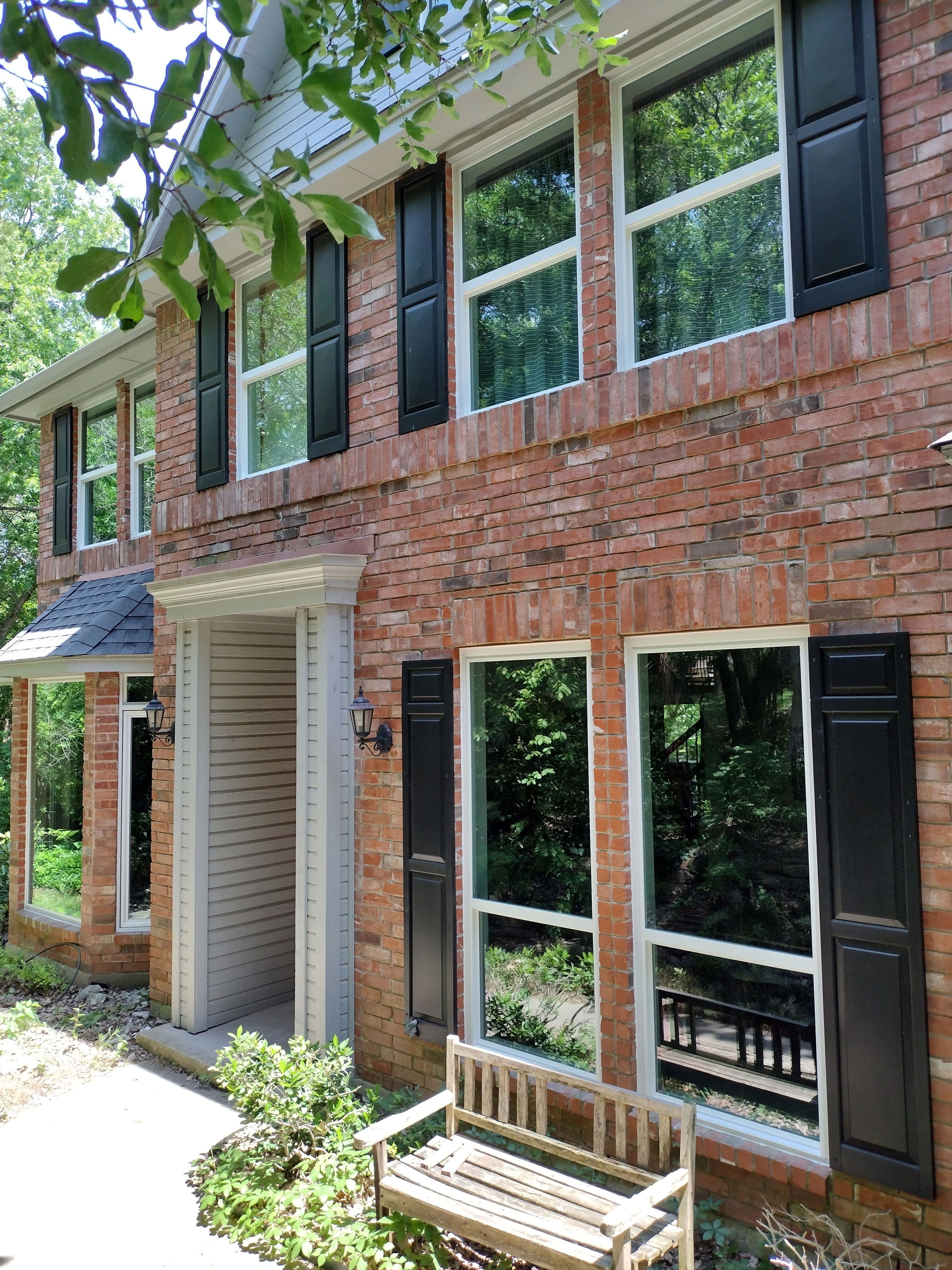Two-story colonial brick home with white framed windows and black shutters