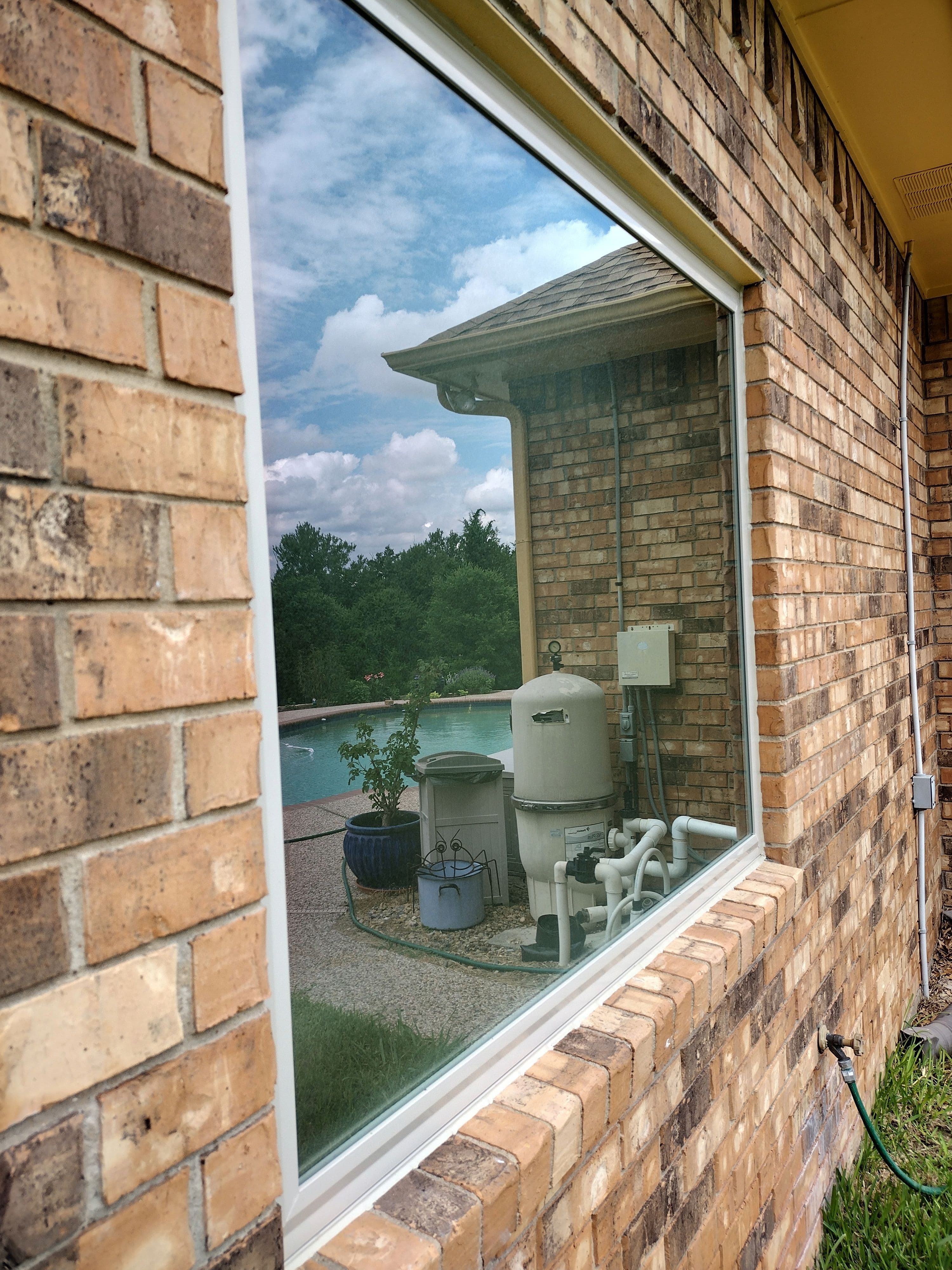 Large picture window on brick exterior with pool and backyard view