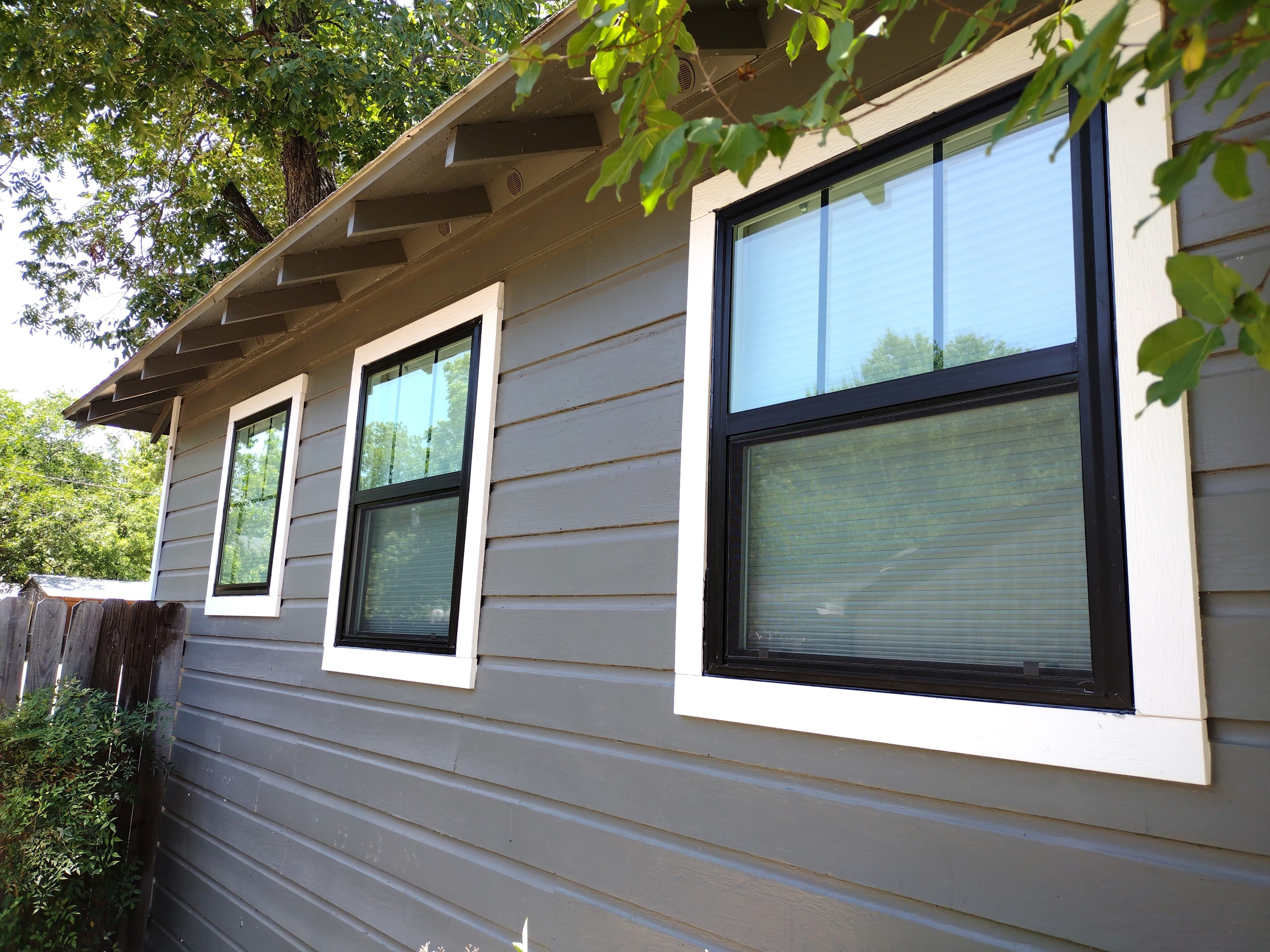 Modern black-framed windows with white trim on gray wood siding
